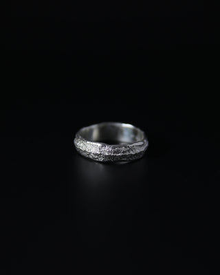 Silver ring with a textured surface on a black background
