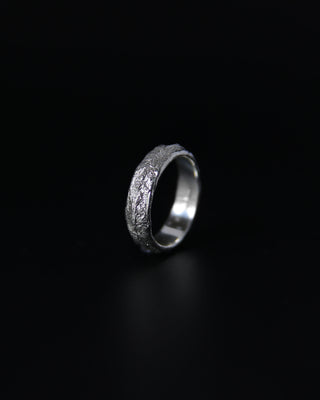 Silver ring with intricate design on a black background