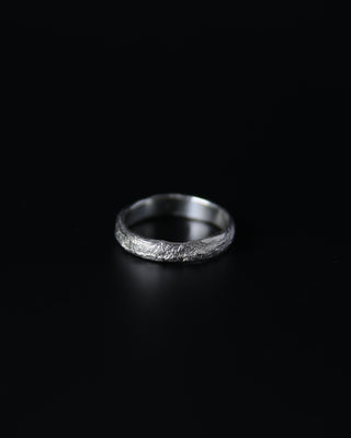Silver ring with a textured surface on a black background