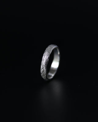 Silver ring with textured surface on a black background