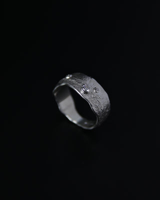 Silver ring with a textured band on a black background