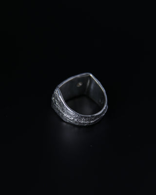 Silver ring with a textured surface on a black background