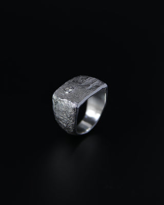 Sterling silver signet ring with a textured surface and a moissanite stone on a black background