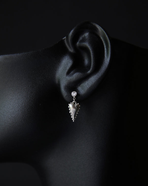 Moissanite and heart dangle earring worn on an ear against a dark background