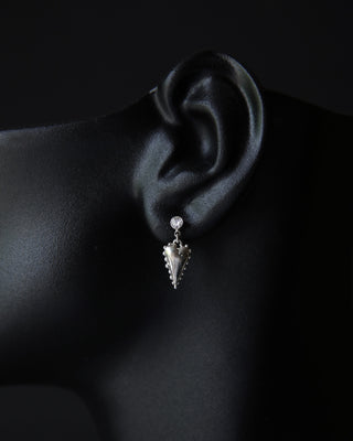 Moissanite and heart dangle earring worn on an ear against a dark background