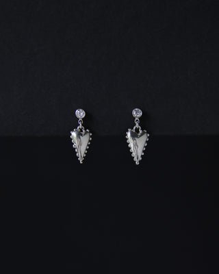 Pair of silver earrings with hearts and moissanite stones on a black background