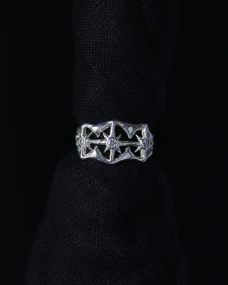 Silver ring with intricate design on a black background