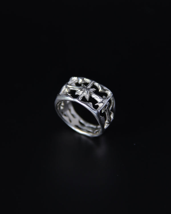 Silver ring with intricate north star design on a black background