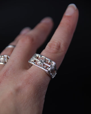 Sterling silver band ring with star detailson a finger against a black background