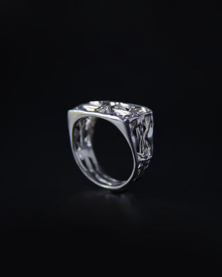 Silver ring with intricate design on a black background