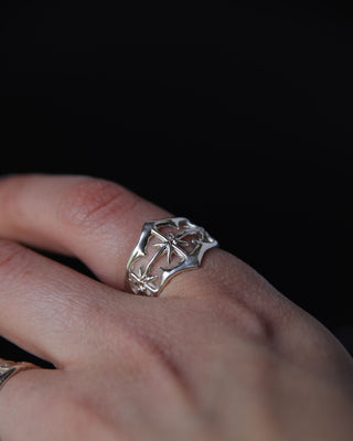 Silver ring with a unique star design on a finger against a dark background