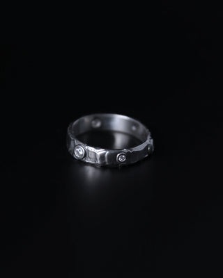 Silver ring with embedded moissanite stones on a black background