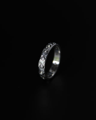 Silver ring with embedded moissanite stones on a black background